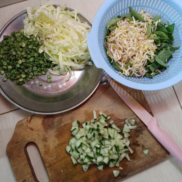 Iris timun, kubis, dan kacang panjangnya, kemudian petik kemanggi daunnya saja dan cuci bersih tauge, sisihkan.