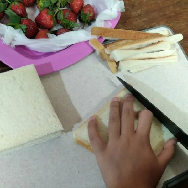 Rendam strawberry dalam air garam selama 15 menit, kemudian bilas. Tiriskan di atas tissue. Buang pinggiran roti tawar