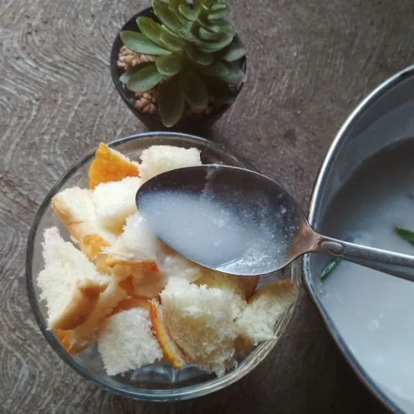 Tuang rebusan santan di atas potongan roti tawar, sajikan selagi hangat