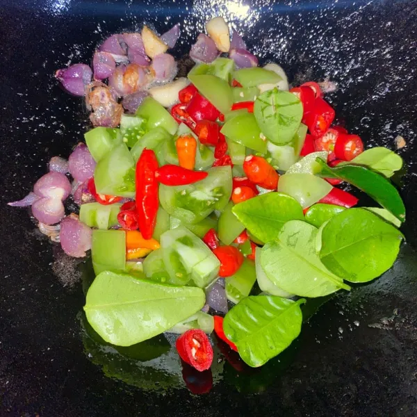 Panaskan minyak, tumis bawang merah dan bawang putih sampai harum. Tambahkan tomat hijau, cabe merah besar, cabe rawit dan daun jeruk. Aduk-aduk sampai layu dan tomat matang.