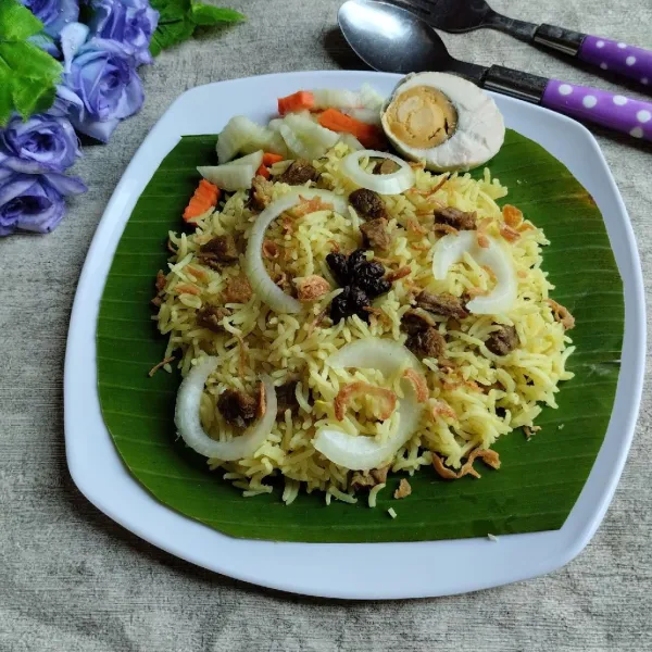 Ambil secukupnya nasi briyani hangat. Tambahkan telur asin, acar, kismis dan juga bawang goreng. Sajikan.