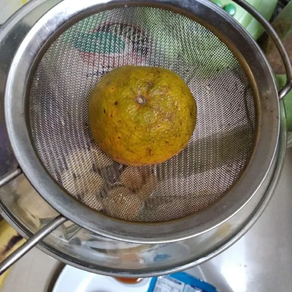Peras jeruk di atas blender menggunakan saringan teh.