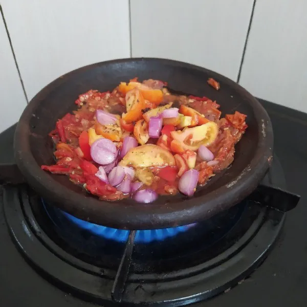 Masak cobek di atas kompor, tambahkan irisan bawang merah dan tomat.