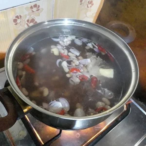 Masukkan bumbu yang sudah diiris (kecuali tomat) ke dalam rebusan kacang merah.