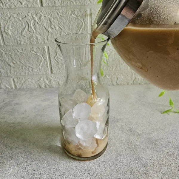Masukkan es batu ke dalam gelas saji, kemudian tuang roasted milk tea hingga gelas penuh