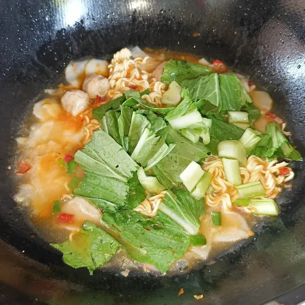 Masukkan sawi dan daun bawang, aduk-aduk sampai sedikit layu.