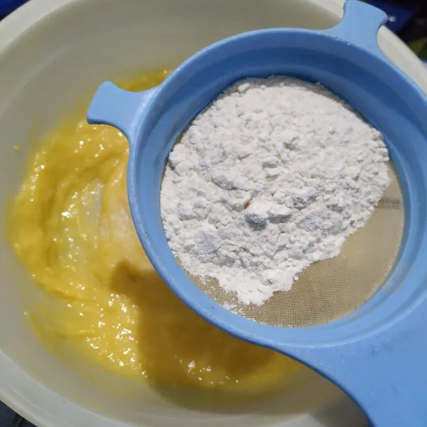 Tambahkan tepung terigu sambil diayak, lalu aduk rata kembali