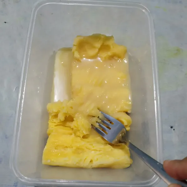 Buang sumbu tape lalu haluskan. Tambahkan susu kental manis, lalu aduk rata