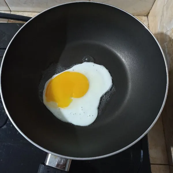 Masukkan telur ke dalam teflon yang belum terlalu panas. Beri 3 sdm air di pinggiran teflon agar telur tidak gosong. Bumbui telur dengan garam dan lada hitam bubuk. Setelah putihnya matang, angkat. Sajikan dengan nasi goreng.