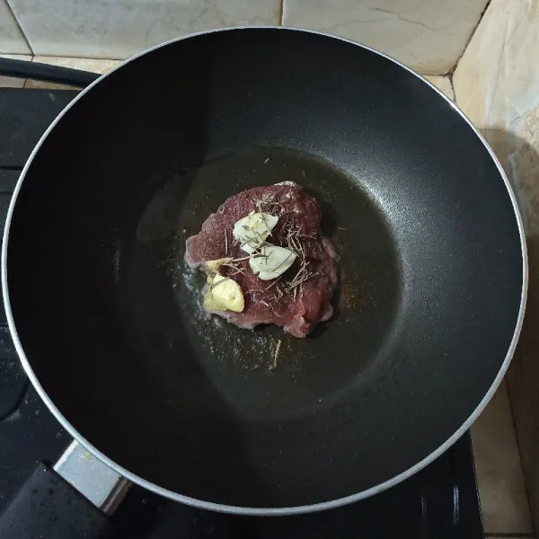 Geprek bawang putih, masukkan ke dalam teflon dengan butter. Taburi lagi dengan garam, lada hitam dan rosemary kering.