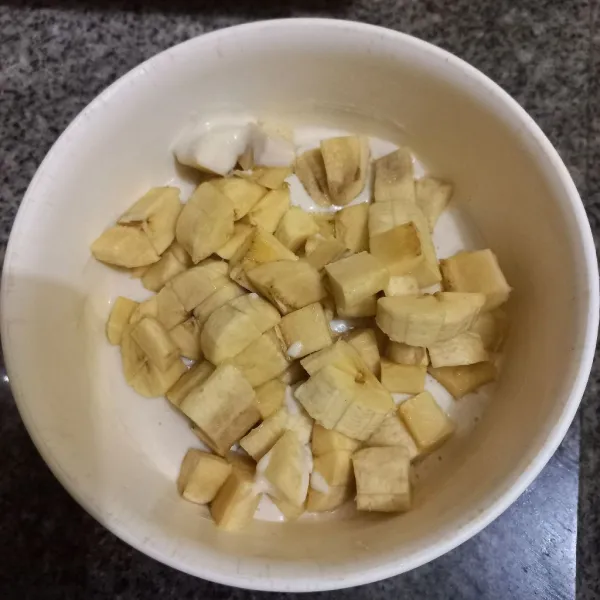 Masukkan pisang ke dalam adonan tepung, aduk rata.