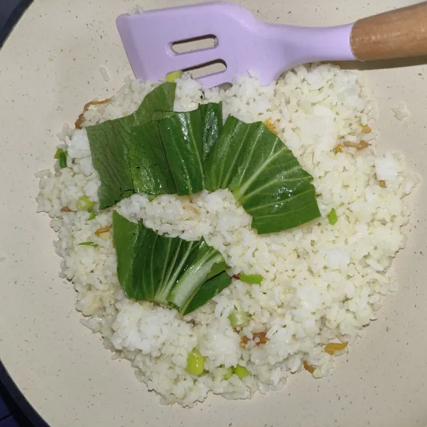 Lalu tambahkan sayur pakcoy, masukan kaldu bubuk dan garam, aduk-aduk sampai sayur layu, setelah itu pindahkan nasi goreng ke piring saji.