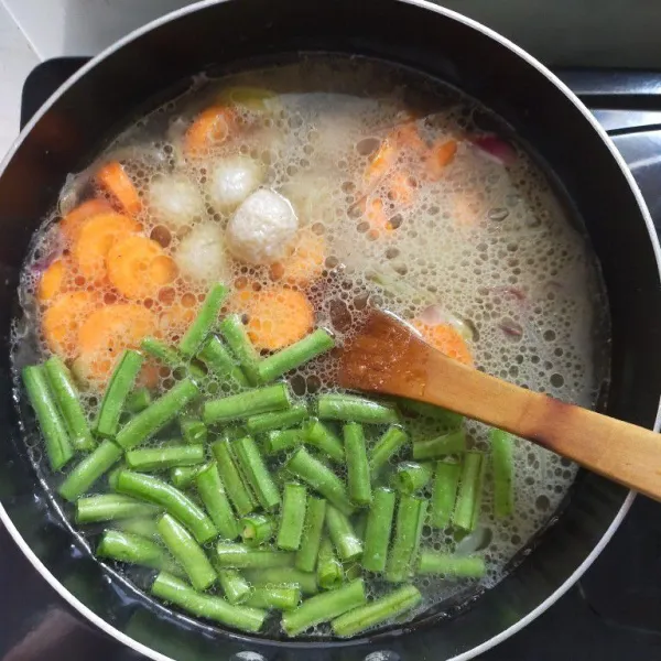 Setelah kuah mendidih, masukkan wortel, bakso ikan, dan buncis, masak hingga sayuran empuk.