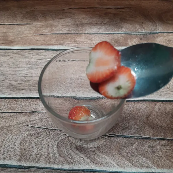 Masukkan strawberry yang sudah dipotong-potong ke dalam gelas.