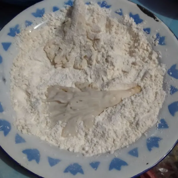 Benamkan jamur ke dalam tepung, tekan agar tepung menempel. Sedikit dipipihkan dan dilebarkan.