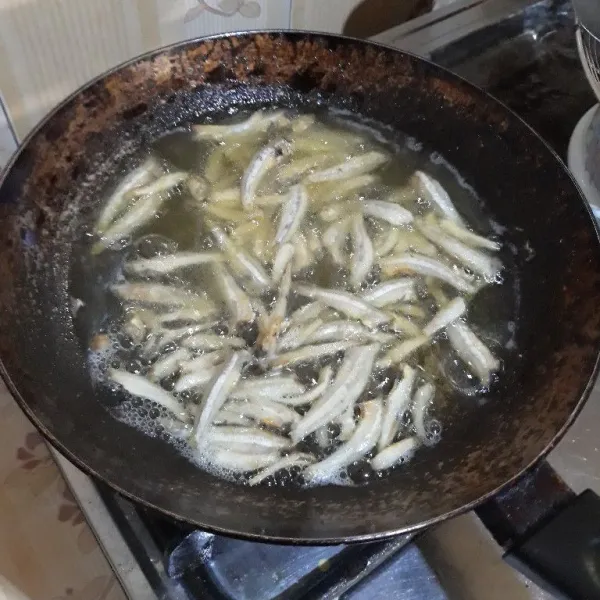 Rendam ikan teri dengan air panas selama 5 menit, goreng dengan minyak secukupnya hingga kering dan sedikit kecokelatan. Angkat dan tiriskan.