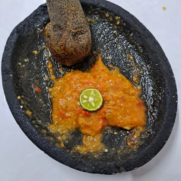 Tambahkan jeruk limau, tekan dengan ulekan agar airnya keluar, aduk rata sambal. Sajikan dengan terong goreng.