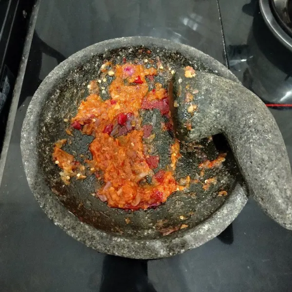 Masukkan cabai merah, cabai rawit, bawang merah dan bawang putih ke dalam cobek lalu haluskan.