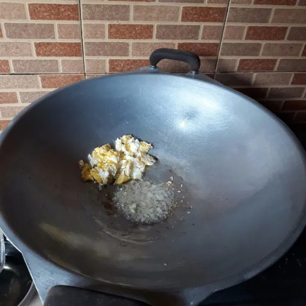 Sisihkan telur di pinggir wajan lalu tumis bawang putih yang sudah dicincang hingga harum.