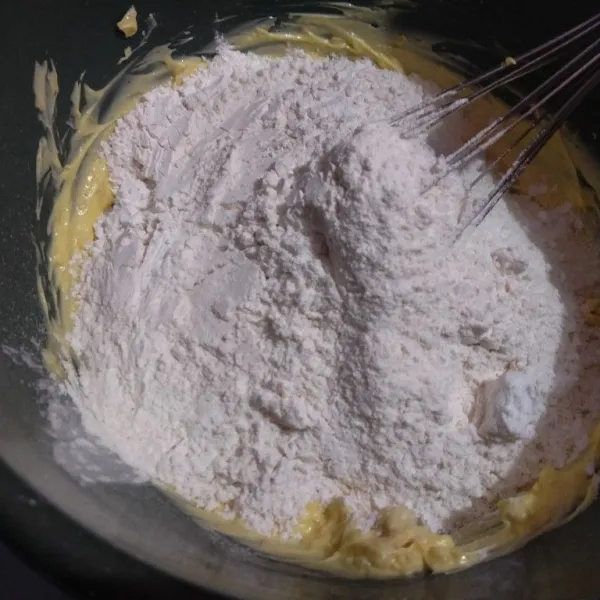 Kemudian masukkan susu bubuk, tepung maizena, dan tepung terigu. Aduk menggunakan spatula sampai membentuk adonan padat