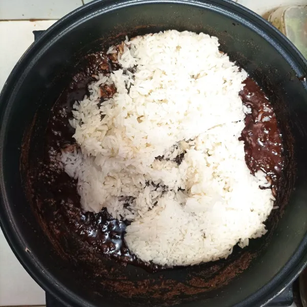 Lalu masukkan beras ketan yang sudah dikukus ke dalam larutan gula. Aduk-aduk hingga airnya surut dan lengket