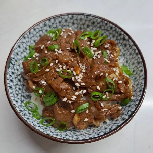 Siapkan nasi dalam mangkuk, beri tumisan daging. Taburi daun bawang dan wijen sangrai lalu sajikan.