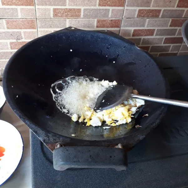 Sisihkan telur pada pinggir wajan, lalu tumis bawang putih hingga harum dan campurkan dengan telur, aduk rata.