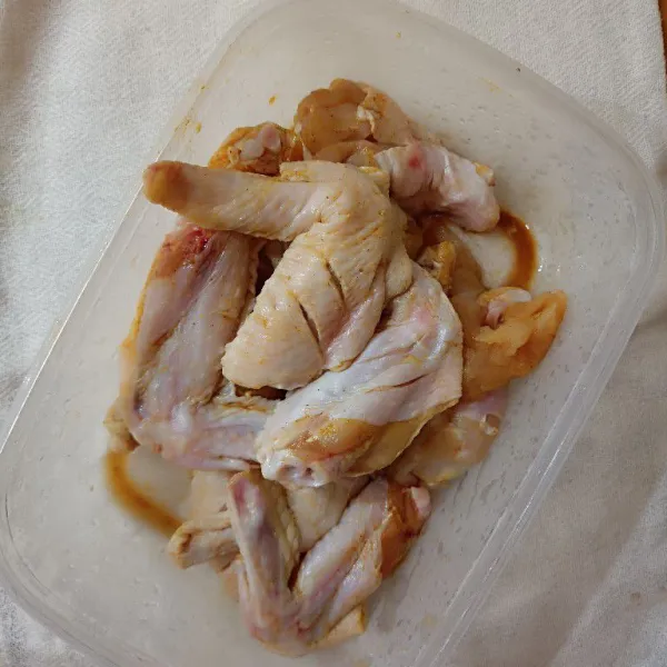 Potong sayap ayam menjadi 2 bagian. Lalu marinasi dengan 1 sdm bumbu ayam goreng instan.
