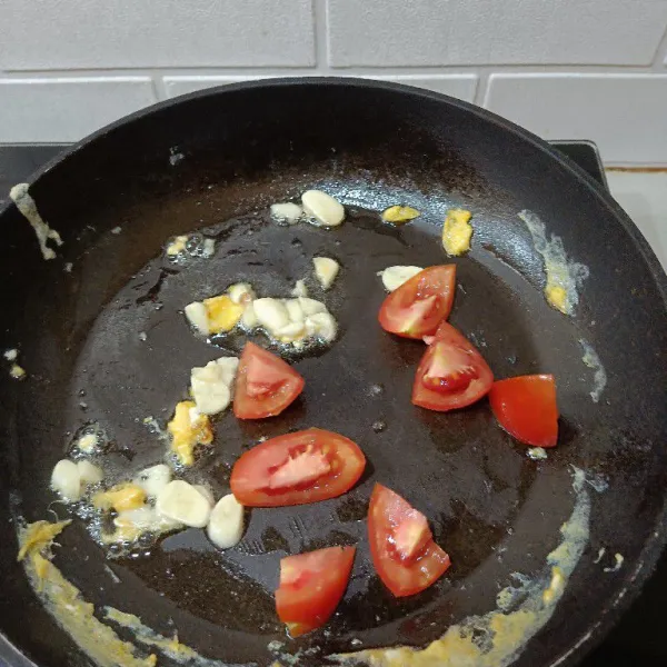 Sisa goreng telur kita pakai untuk menumis bawang putih sampai harum dan kemudian masukkan irisan tomat. Aduk sampai tomat agak layu.