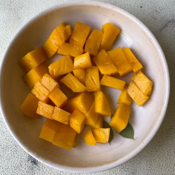 Kupas dan potong-potong mangga.