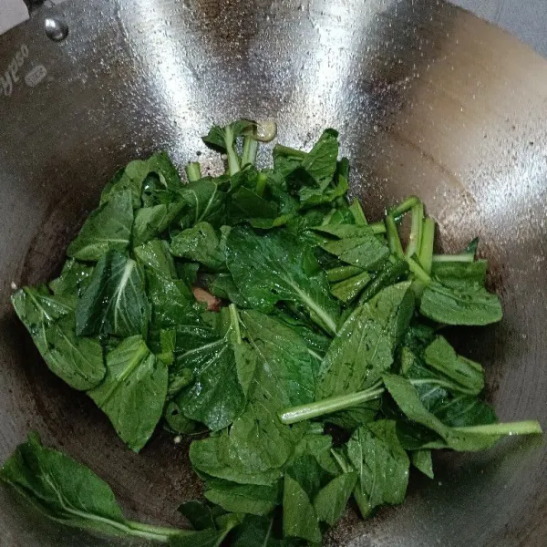 Masukkan sawi aduk merata . Tumis 1 menit atau sampai warna daun agak gelap.