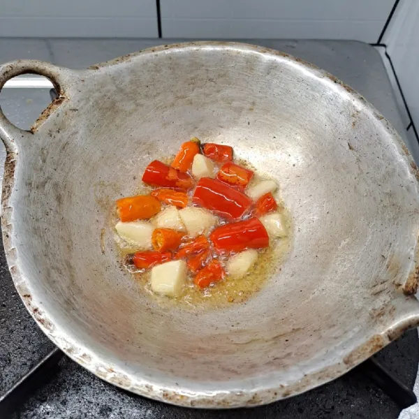 Potong-potong cabe merah, cabe rawit dan bawang putih lalu goreng sebentar asal layu.