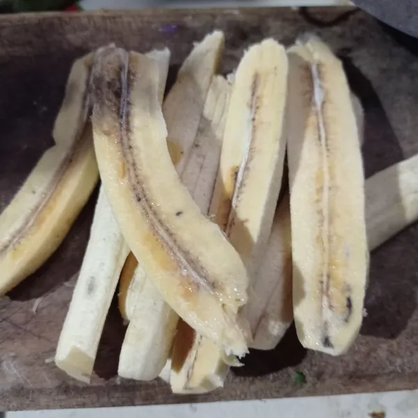 Kupas pisang, lalu belah jadi dua bagian.