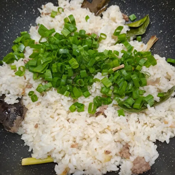 Masukkan irisan daun bawang, aduk rata, masak sampai daun bawang layu. Angkat dan sajikan nasi goreng dengan irisan telur dadar dan bawang merah goreng.