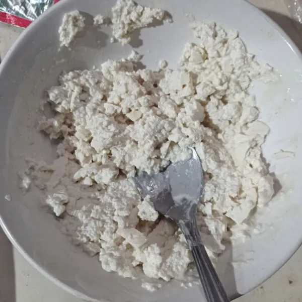 Haluskan tahu menggunakan garpu.