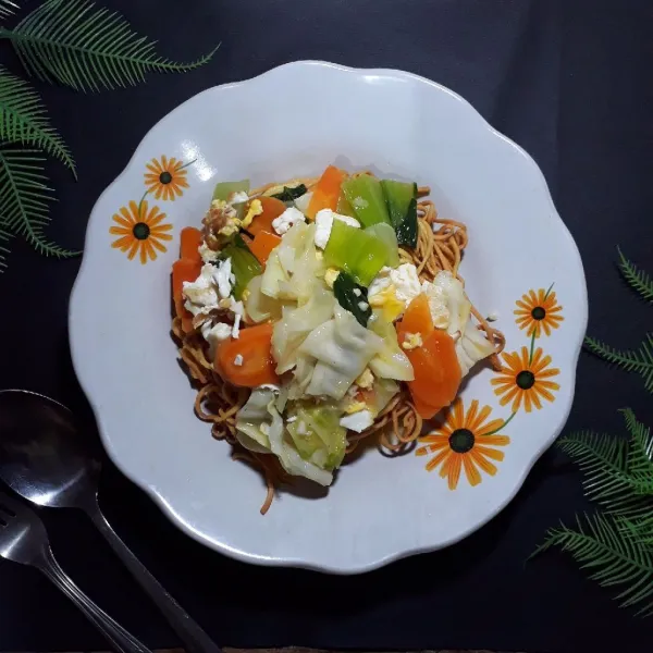 Tata mie goreng diatas piring, siram dengan capcay panas, sajikan.