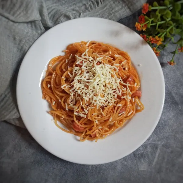 Siapkan piring saji dan tuang spaghetti kemudian taburi dengan keju parut dan oregano kering.