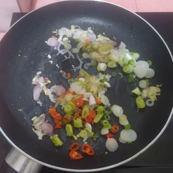 Tumis bawang merah dan bawang putih sampai harum lalu masukkan irisan cabe dan daun bawang.