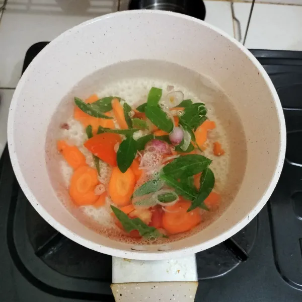 Masukkan irisan wortel dan bawang merah, tunggu hingga wortel empuk