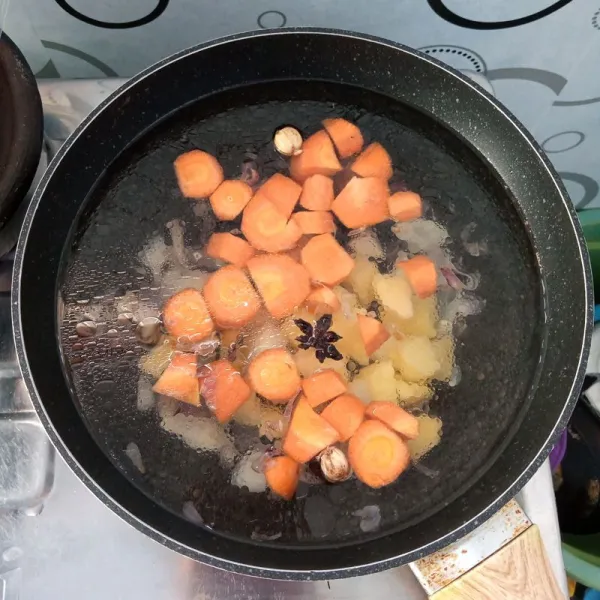 Tambahkan air, wortel dan kentang. Aduk rata. Masak sampai empuk.