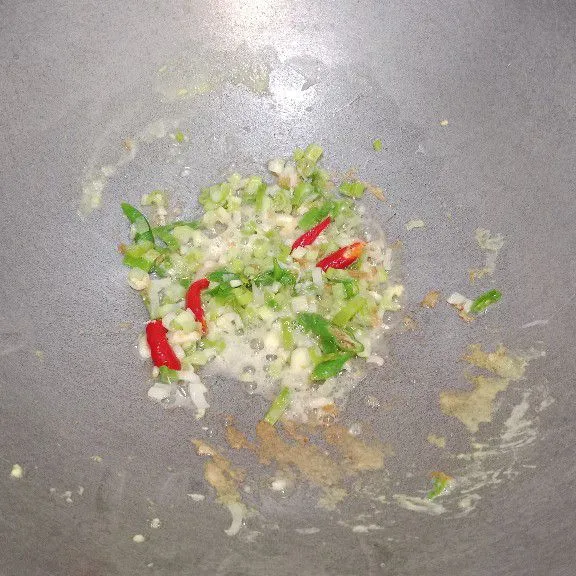 Tumis bawang putih dan daun bawang hingga harum, kemudian masukkan irisan cabai, tumis sampai cabai sedikit layu.
