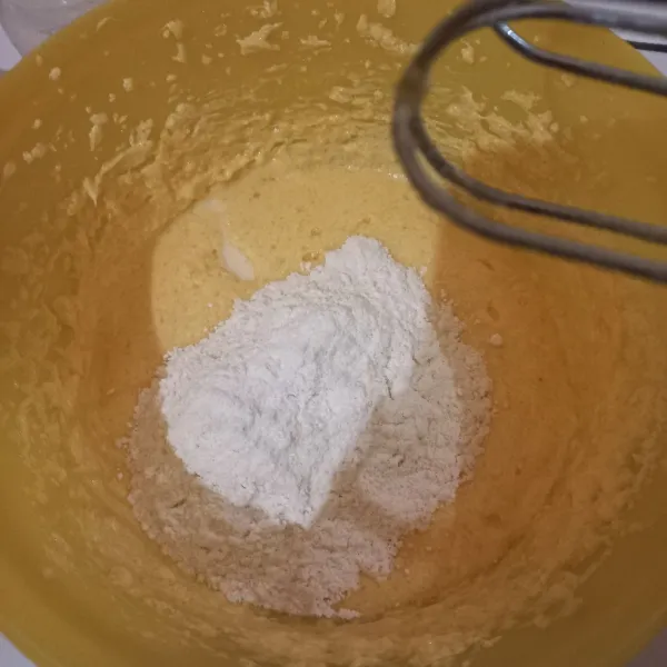 Campurkan tepung terigu, baking powder, dan garam. Setelah itu masukkan sedikit demi sedikit bergantian dengan susu cair ke dalam adonan telur. Aduk hingga kaku dan berjejak