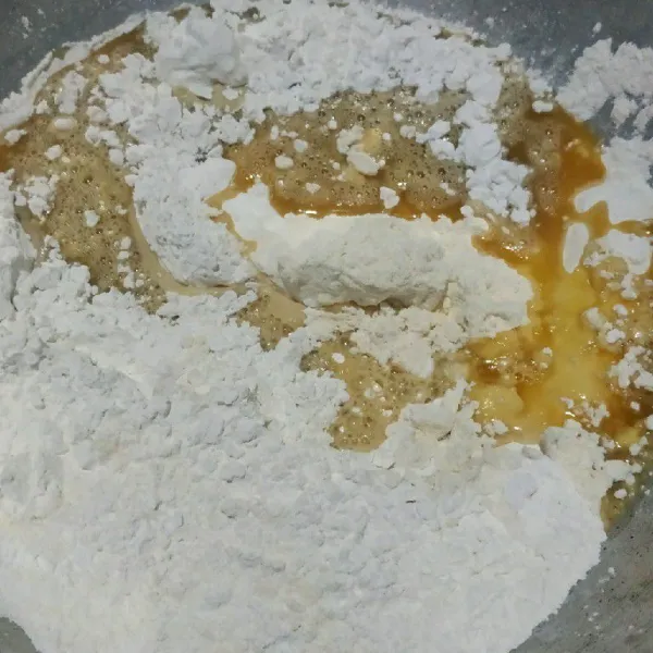 Campur jadi 1 tepung beras dan tepung terigu lalu tuang sebagian air gula sambil di uleni hingga tercampur rata.