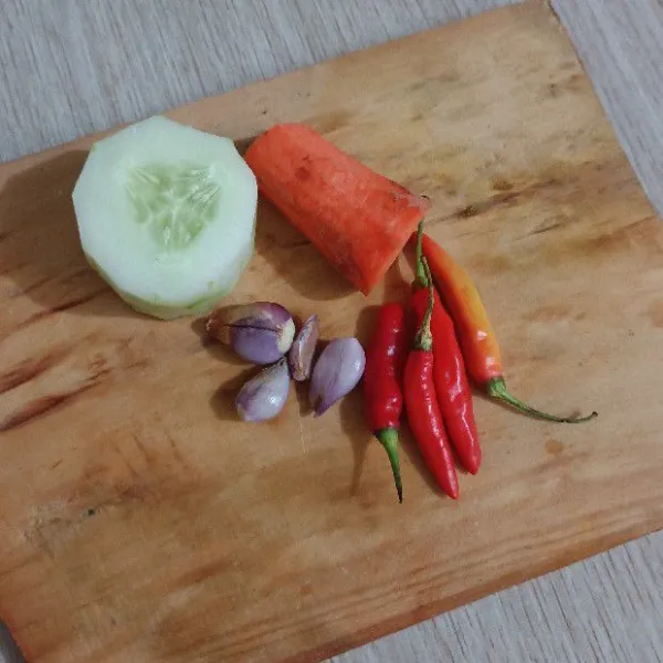 Kupas timun, wortel, dan bawang merah.