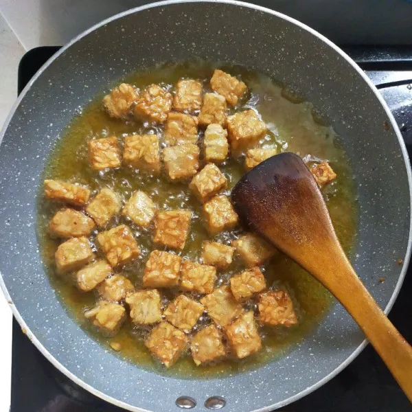 Panaskan minyak, kemudian goreng tempe sampai kuning kecoklatan, lalu angkat dan tiriskan.