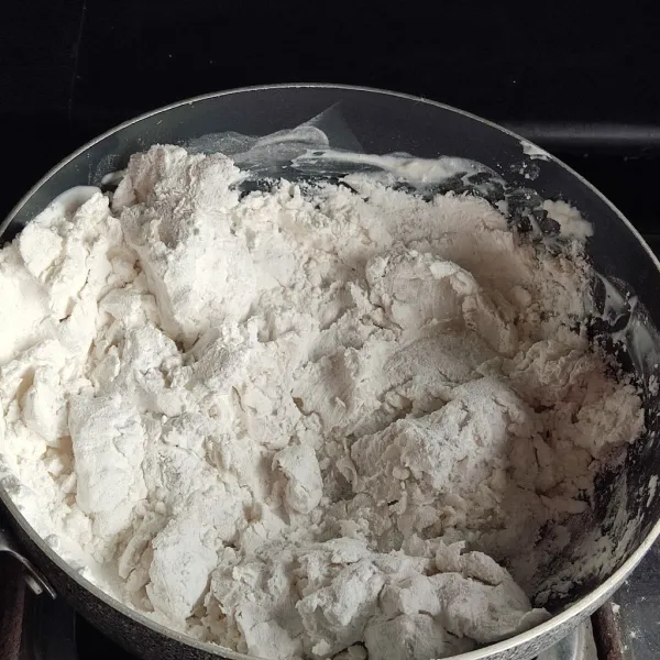 Matikan kompor, masukkan tepung sagu, aduk cepat-cepat hingga kalis dan tidak ada lagi tepung yang menggumpal.