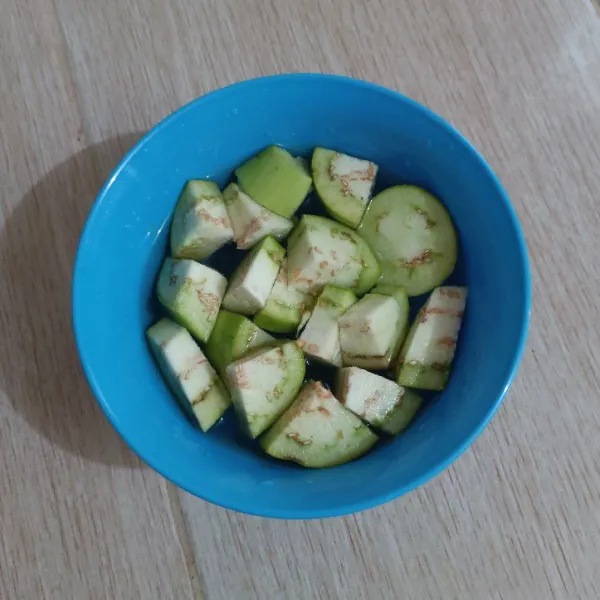 Jupas dan potong terong. Rendam dalam air agar tidak menggelap warnanya.