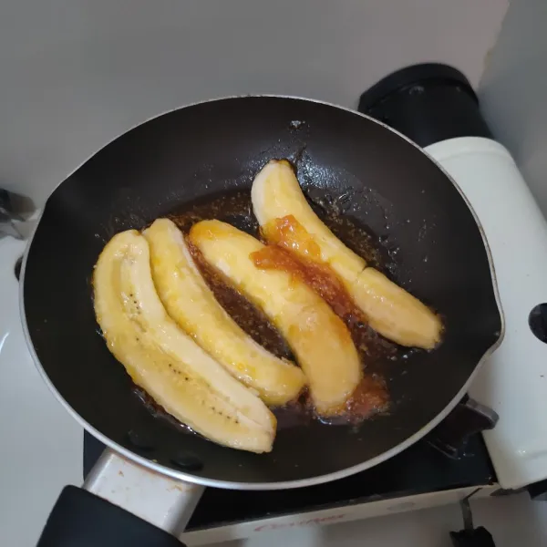 Belah pisang menjadi dua bagian, kemudian baluri merata dengan karamel