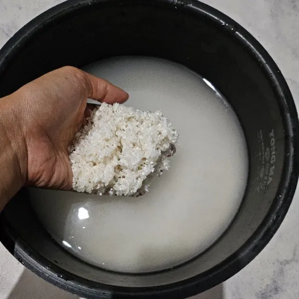 Cuci bersih beras, masukkan ke dalam wajan rice cooker kemudian isi air seperti takaran memasak nasi biasa. Kurangi sedikit takaran airnya karena nanti akan ditambahkan santan lalu sisihkan.