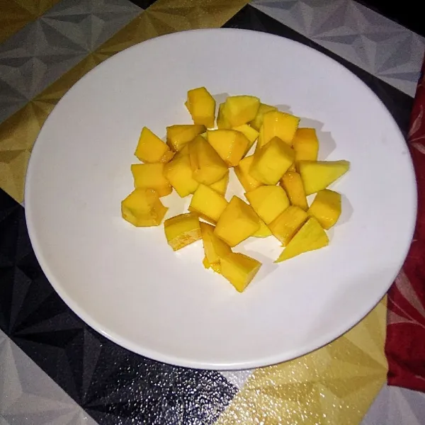 Potong-potong buah mangga menjadi kotak-kotak kecil kemudian sisihkan. Blender hingga halus satu buah mangga dan sisihkan